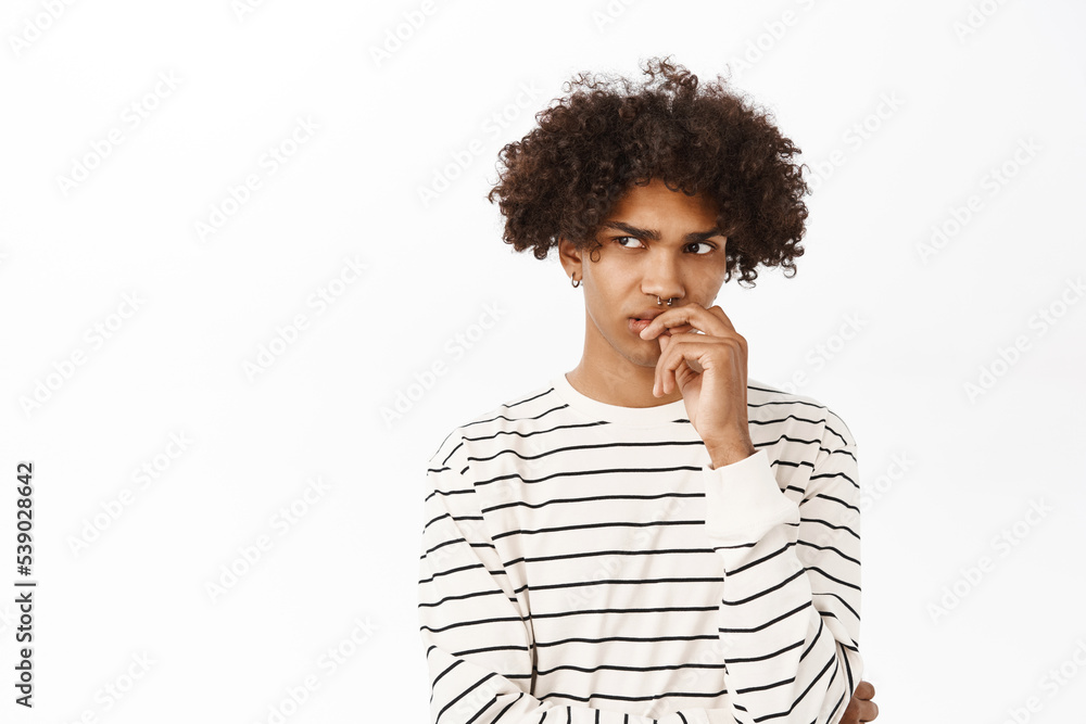 Close up portrait of hispanic guy with curly hair thinking, looking bothered by dilemma, pondering, standing over white background Close up portrait of hispanic guy with curly hair thinking, looking bothered by dilemma, pondering, standing over white background