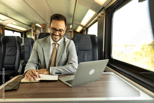 Young business man traveling to work by train, working while traveling, with his laptop and notebook, talking on phone, writing down some goals in notebook. Business people stock photo  © Nemanja