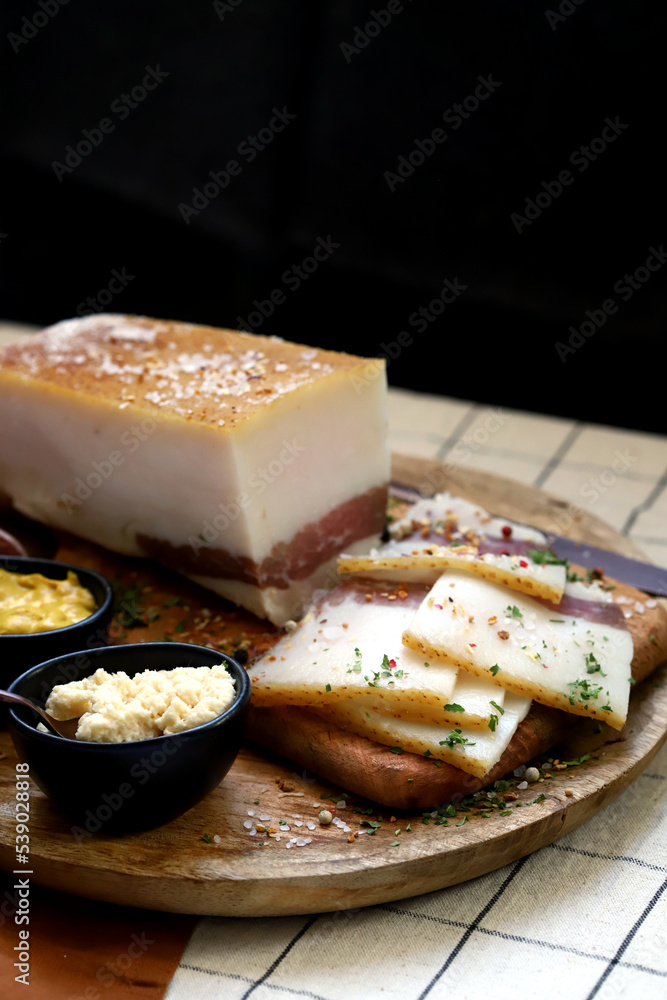 Fresh lard with meat layer on a wooden board with spices, mustard and horseradish. Delicious snack. Bacon. Fresh lard with meat layer on a wooden board with spices, mustard and horseradish. Delicious snack. Bacon.