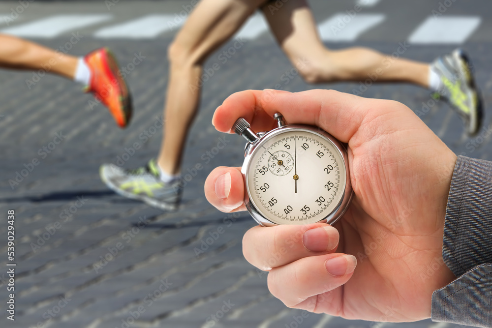 measuring the running speed of an athlete using a mechanical stopwatch. hand with a stopwatch on