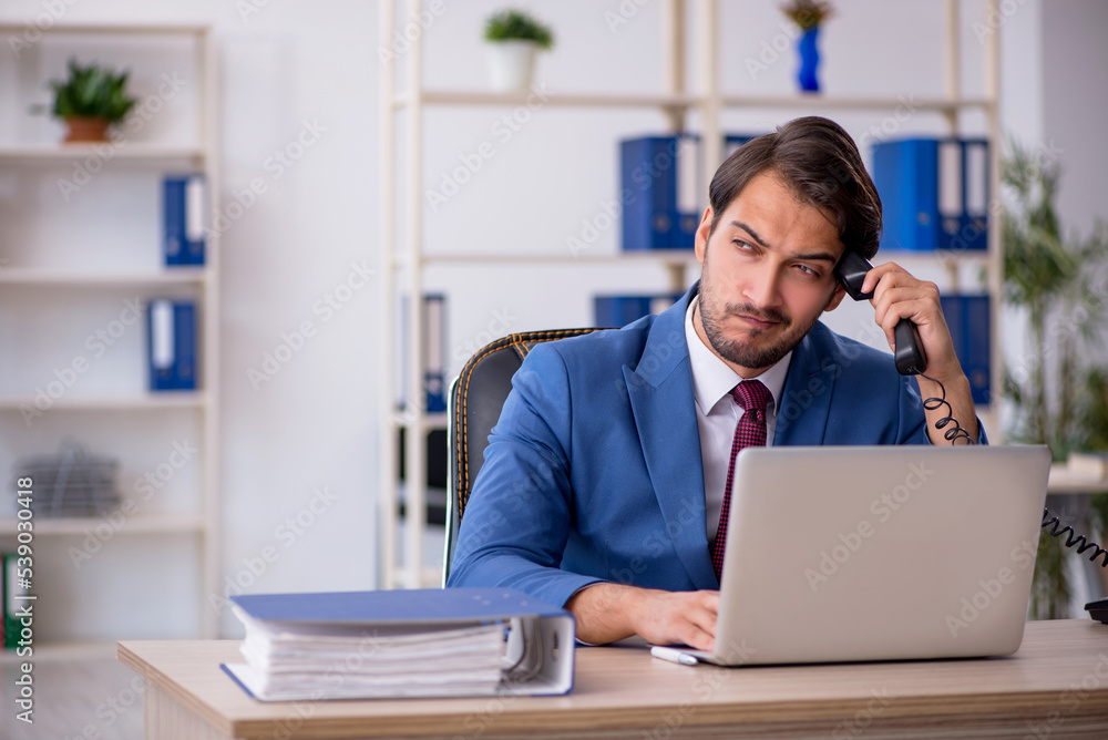 Young male employee and too much work in the office Young male employee and too much work in the office