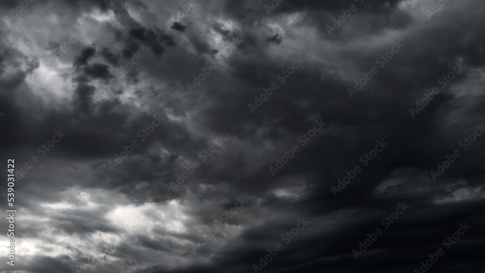 Obraz premium dark dramatic sky with black stormy clouds before rain or snow as abstract background, extreme weather, the sun shines through the clouds, high contrast photo