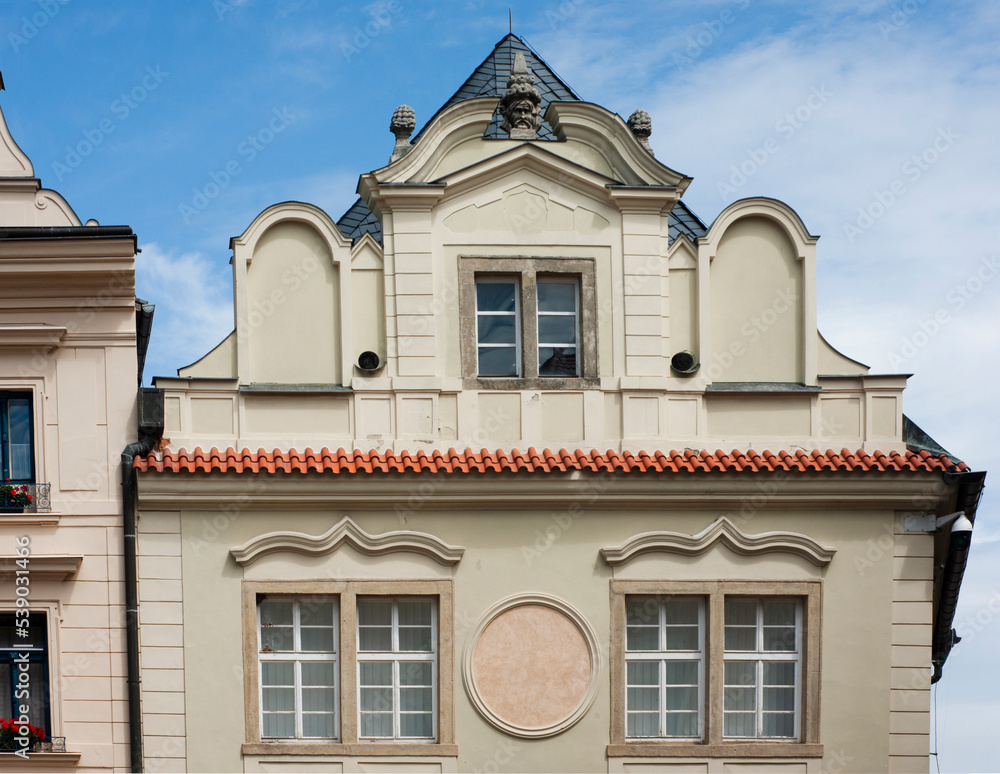 Kutna Hora building with medieval architecture and peaked roof line in Czech Republic, Eastern Europe. Figure head at top of house with gingerbread additions.