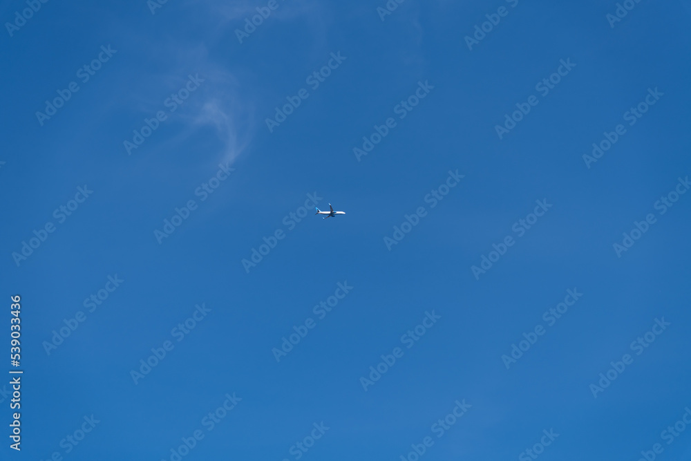 Low angle view of passenger airplane flying in clear blue sky with few cirrus clouds. Copy space for your text. Transportation theme. Low angle view of passenger airplane flying in clear blue sky with few cirrus clouds. Copy space for your text. Transportation theme.
