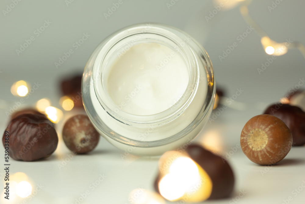 Concept of autumn skincare. Closeup of a jar of moisturizer and chestnuts.