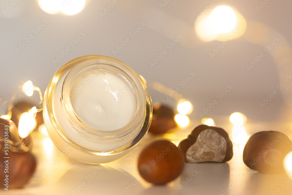 Concept of autumn skincare. Closeup of a jar of moisturizer and chestnuts.