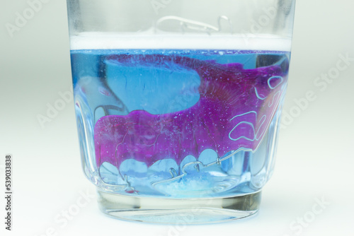 Cleaning a retainer in a glass with a cleansing tablet. 