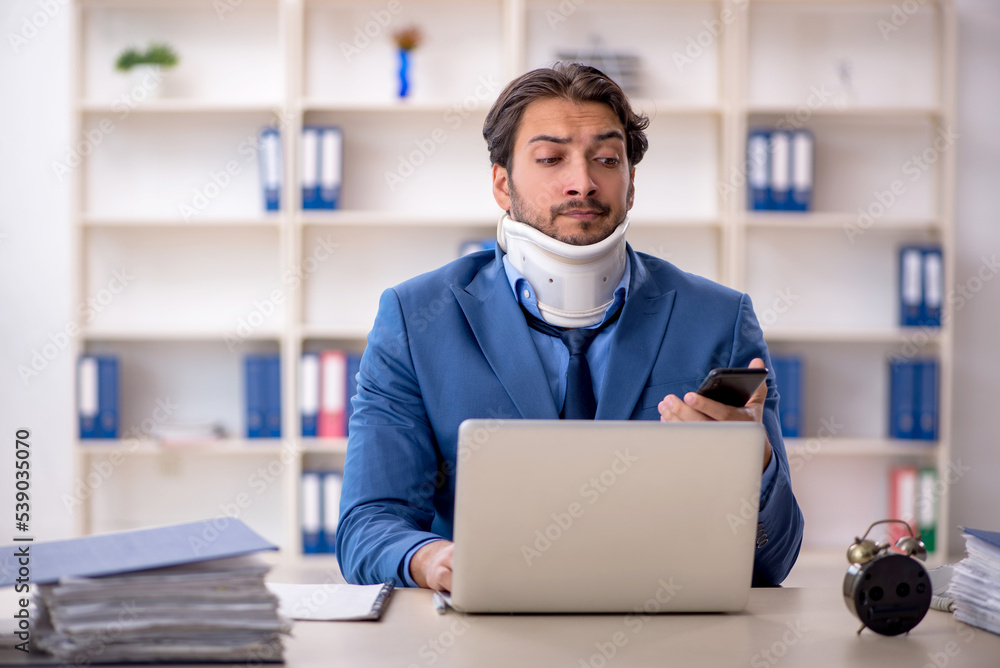 Young male employee after accident sitting at workplace Young male employee after accident sitting at workplace