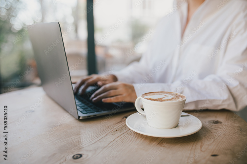 Young woman drinking coffee working online using her laptop. Young woman drinking coffee working online using her laptop.