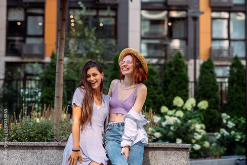 Two young women pose against the background of a building