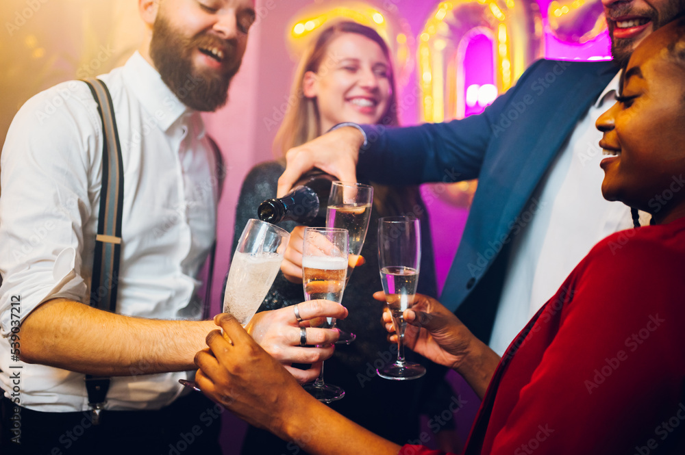 People hands holding flute glasses while pouring champagne People hands holding flute glasses while pouring champagne