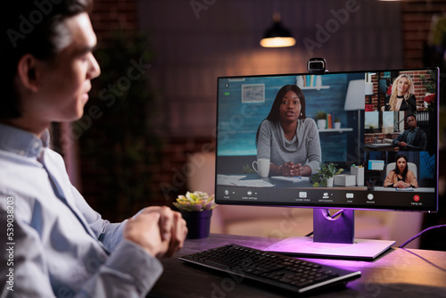 Asian man talking to colleagues on videoconference, attending business meeting online on teleconference call. Usin webcam on computer to chat with people on internet videocall connection.