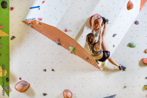 Young woman bouldering in indoor climbing gym
