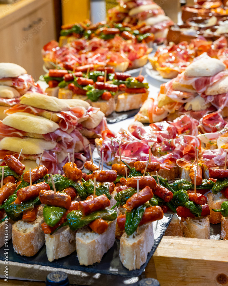 Fototapeta premium Typical snack of Basque Country and Navarre, pinchos or pinxtos, small piece of bread with different toppings, served in bar, Bilbao, Spain