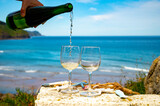 Pouring of txakoli or chacolí slightly sparkling very dry white wine produced in the Spanish Basque Country, served outdoor with view on Bay of Biscay, Atlantic Ocean.