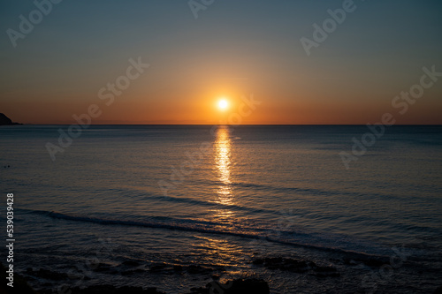 Sunset in calm waters of Atlantic ocean and clear sky