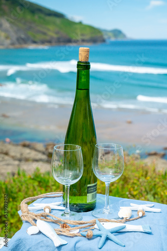 Tasting of txakoli or chacol   slightly sparkling very dry white wine produced in the Spanish Basque Country  served outdoor with view on Bay of Biscay  Atlantic Ocean.
