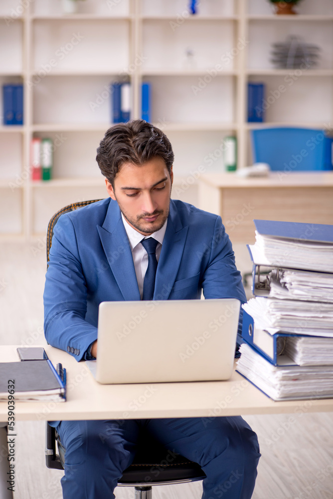 Young male employee and too much work in the office