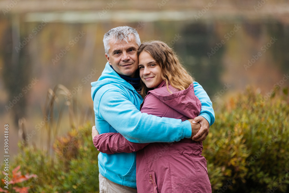 Middle aged father and daughter hug each other outdoors Middle aged father and daughter hug each other outdoors