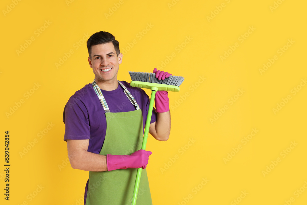 Man with green broom on orange background, space for text