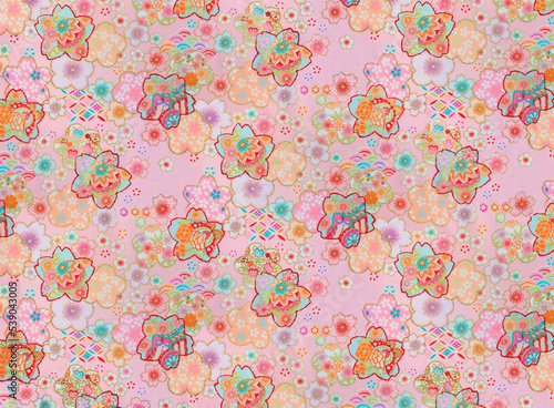 Photograph of a traditional Japanese furoshiki cloth made in cotton fabric with a pattern design illustrated with flowers like cherry, plum, cosmos or peony flowers against a pastel pink background.