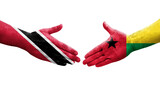 Handshake between Guinea Bissau and Trinidad Tobago flags painted on hands, isolated transparent image.