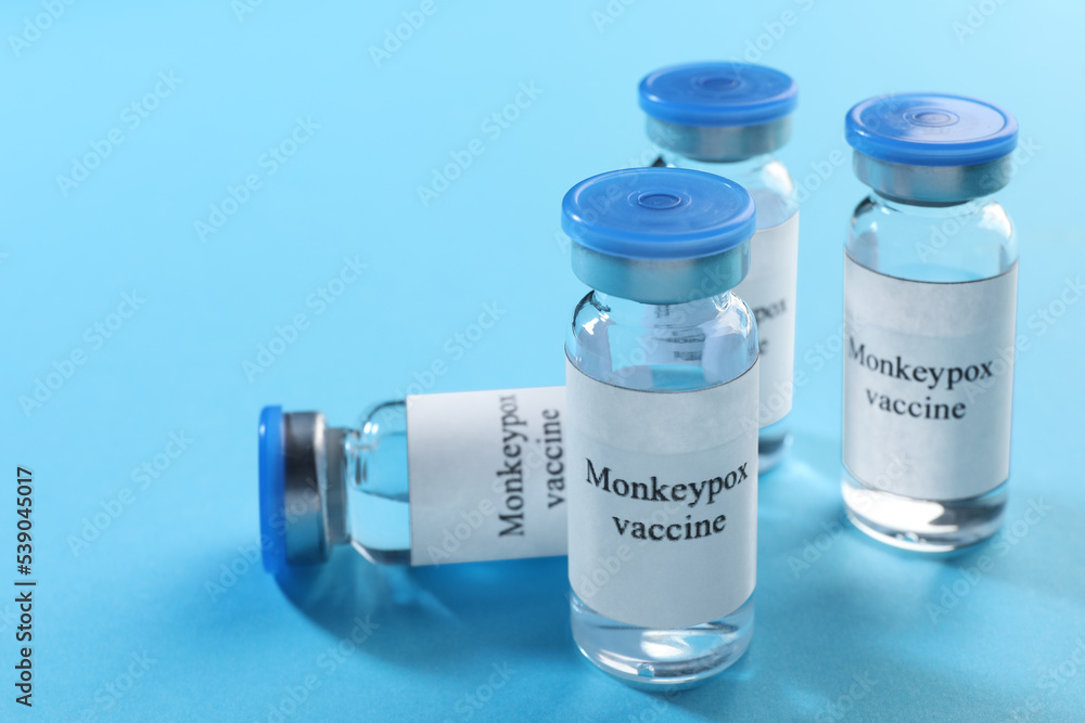 Monkeypox vaccine in glass vials on light blue background, space for text Monkeypox vaccine in glass vials on light blue background, space for text