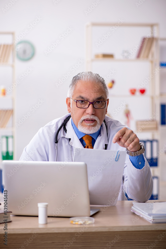 Old male doctor working in the clinic Old male doctor working in the clinic
