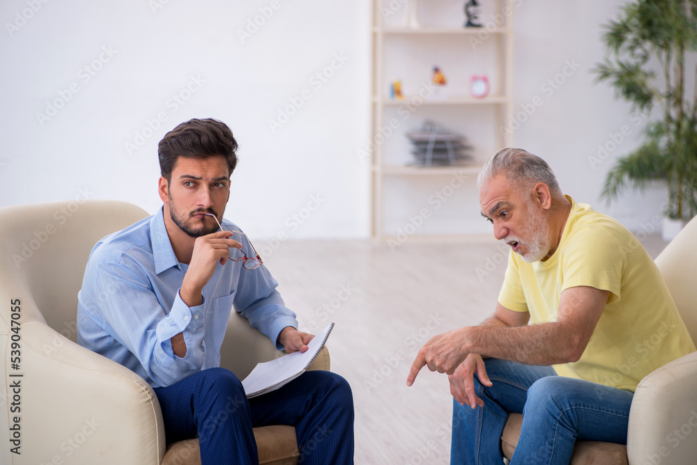 Old man visiting young male psychotherapist Old man visiting young male psychotherapist