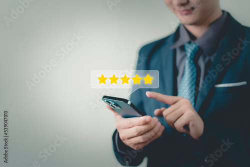 Fototapeta Naklejka Na Ścianę i Meble -  Businessman hand using smart phone and give five star symbol to increase rating of the product and service concept, Customer service experience and business satisfaction survey