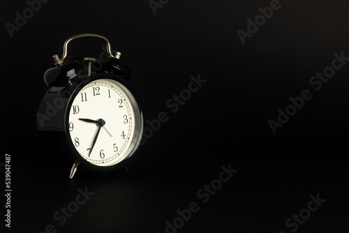 black vintage alarm clock isolated on black background, Time concept, 9:35 o'clock. Morning, reminder.