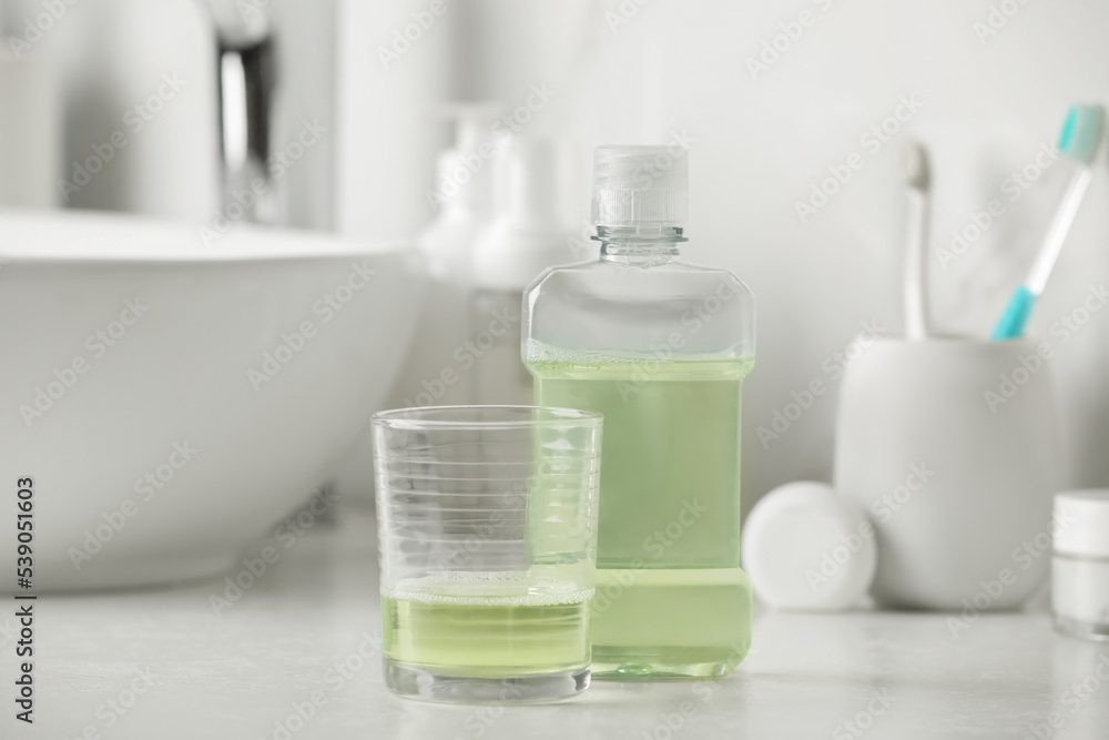 Mouthwash and glass on white countertop in bathroom Mouthwash and glass on white countertop in bathroom