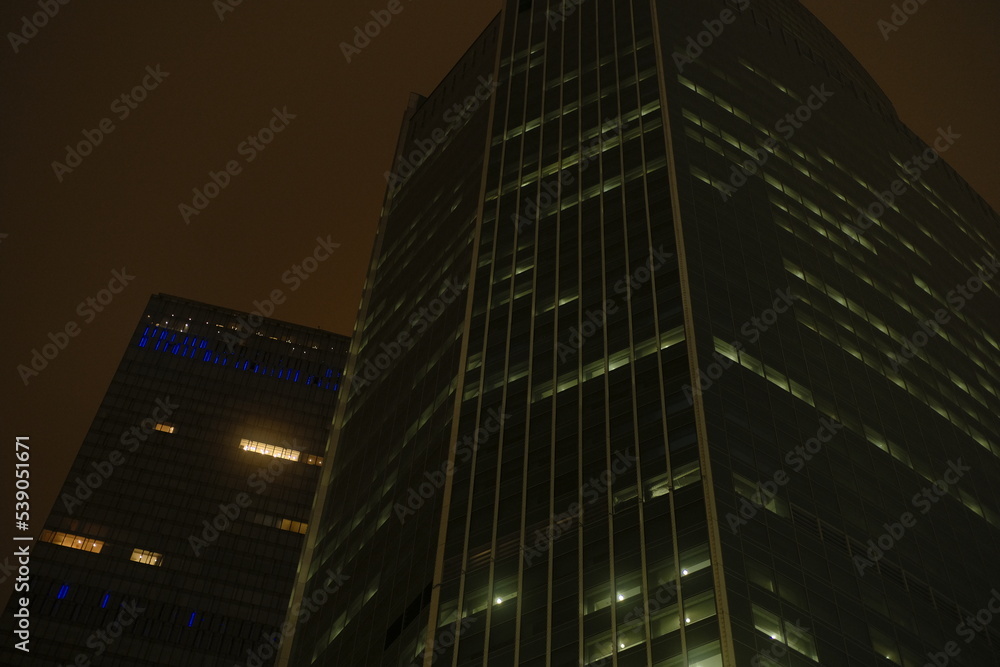 Facade of modern skyscraper with glass walls. From below of contemporary tall skyscraper with glass walls at night in downtown.