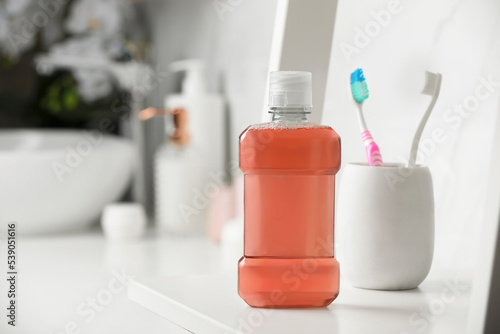 Bottle of mouthwash on white shelf in bathroom, space for text