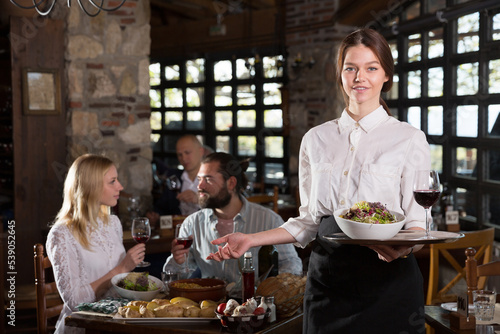Professional waitress greeting customers at table in rustic restaurant. High quality photo © JackF