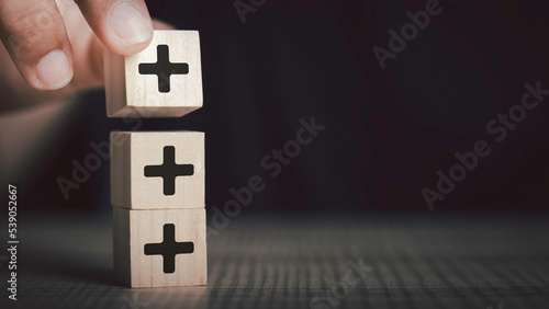 Plus sign in wooden cube block stacking. Addition and positive mindset thinking  such as profit, benefits, development, CSR represented, motivation, increase concept and copy space. photo