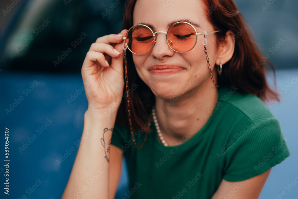 Beautiful fashionable young woman in glasses posing near car Beautiful fashionable young woman in glasses posing near car