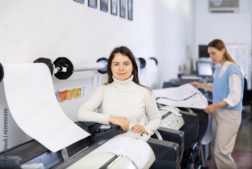 Obraz premium Female worker checking paper in printing press workshop