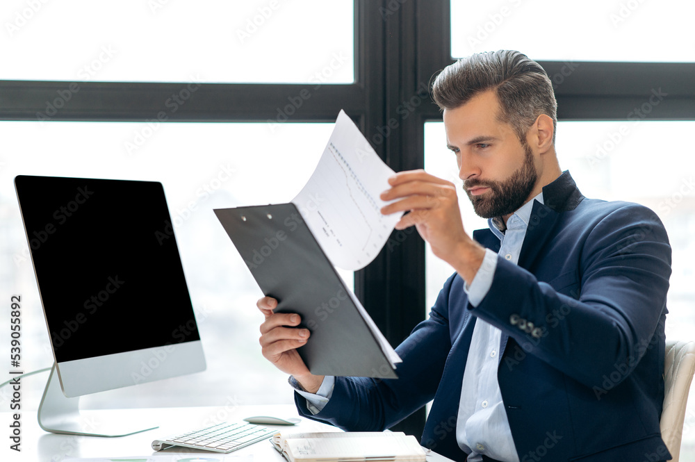 Serious clever successful caucasian financial director, ceo, executive, analyzing financial graphs, plans strategy and business plan while sit at workplace in the office. Work with financial documents Serious clever successful caucasian financial director, ceo, executive, analyzing financial graphs, plans strategy and business plan while sit at workplace in the office. Work with financial documents