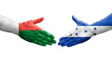 Handshake between Honduras and Madagascar flags painted on hands, isolated transparent image.