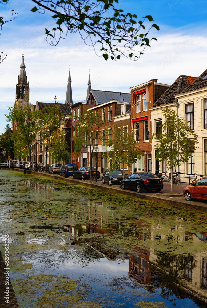 Canal of Delft embankment in afternoon with view of New Church in background.