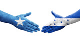 Handshake between Honduras and Somalia flags painted on hands, isolated transparent image.