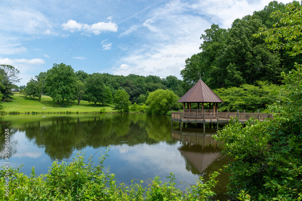 A gazebo reflected in a pond on summer day. A gazebo reflected in a pond on summer day.