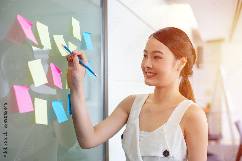 Asian girl writing roadmap planning on sticky note work at office Asian girl writing roadmap planning on sticky note work at office