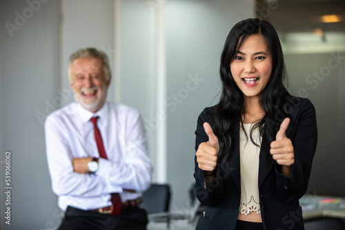 Businesswoman thumbs up and stands smiling confidently and laughing happy in the conference room.