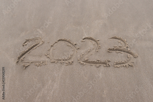 text 2023 on the sand of beach symbol new year 2023