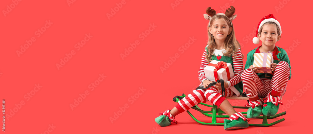 Fototapeta premium Cute little elves with Christmas gifts and sledge on red background with space for text