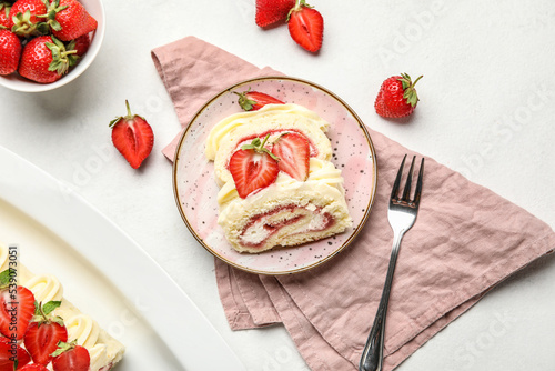 Plate with slices of tasty strawberry roll cake on light background