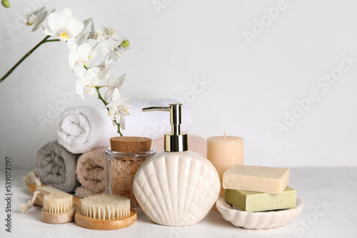 Set of bath supplies with orchid flower on light background