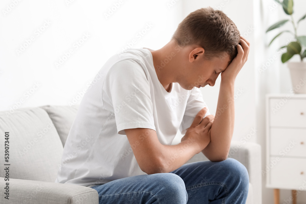 Stressed young man sitting on sofa at home Stressed young man sitting on sofa at home